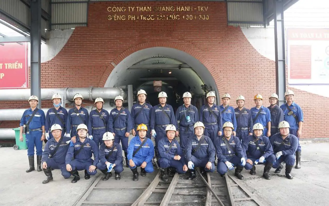 Nhóm học viên nghề mỏ Quang Hanh mặc bảo hộ xanh, đội mũ trước cửa lò