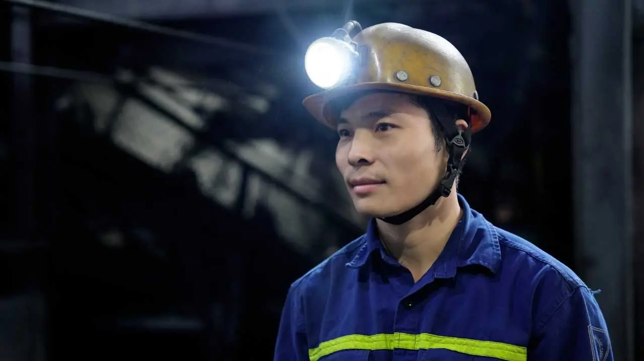 Chân dung công nhân trẻ TKV mặc bảo hộ xanh, đội mũ trong hầm lò